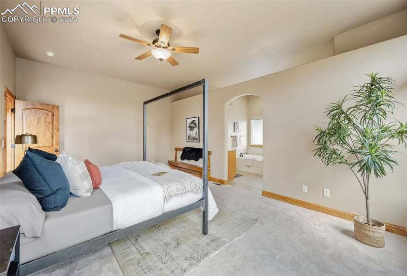 Bedroom featuring ensuite bath, light colored carpet, and ceiling fan