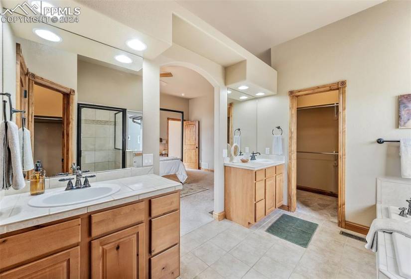 Bathroom featuring oversized vanity, tile floors, and a bath to relax in
