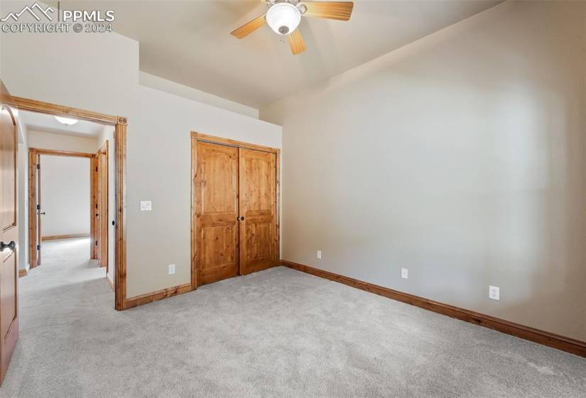 Unfurnished bedroom featuring ceiling fan, a closet, and light carpet