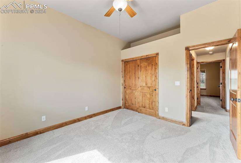 Unfurnished bedroom with ceiling fan, light colored carpet, and a closet