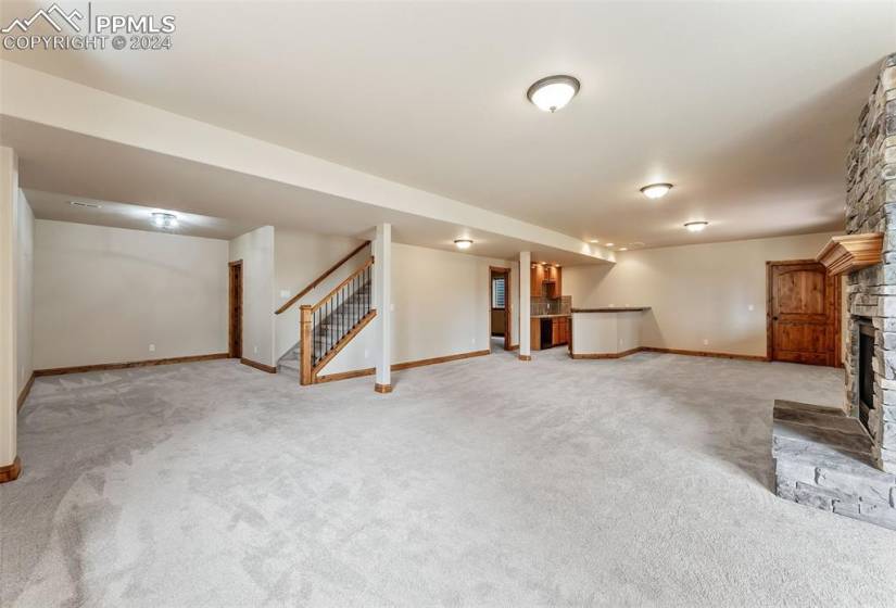 Basement with light carpet and a stone fireplace