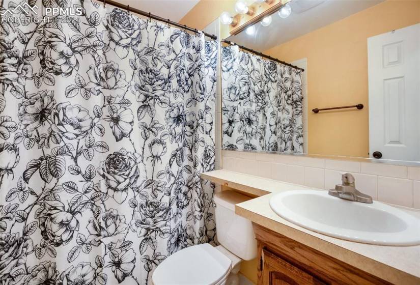 Bathroom with tile walls, tasteful backsplash, toilet, and vanity with extensive cabinet space