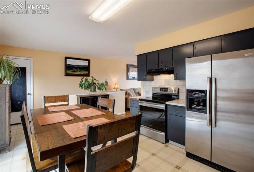Kitchen with backsplash, appliances with stainless steel finishes, and light tile floors