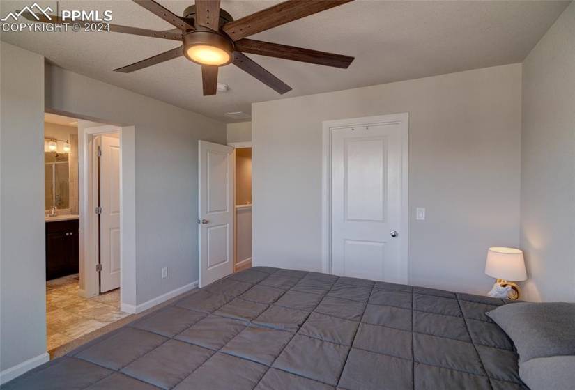 Unfurnished bedroom featuring light tile floors, ensuite bath, a closet, ceiling fan, and sink