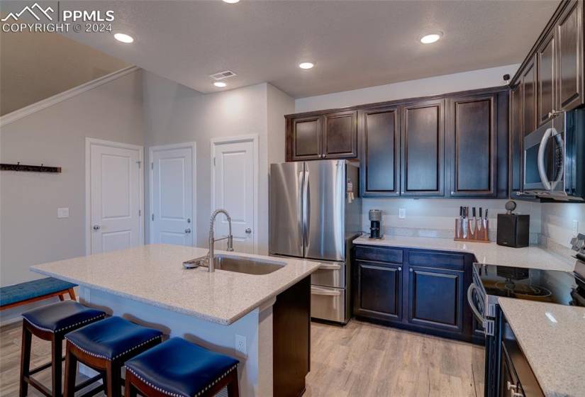 Kitchen featuring appliances with stainless steel finishes, sink, an island with sink, light hardwood / wood-style floors, and dark brown cabinetry