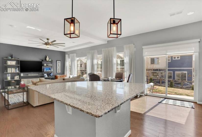 Kitchen with light stone countertops, a center island,  LVT flooring, and pendant lighting