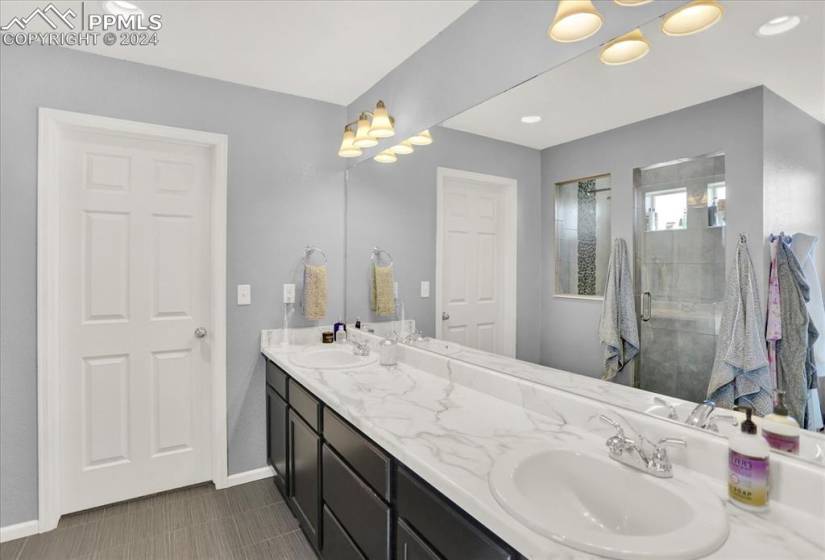 Bathroom with walk in shower, double sink vanity, and tile floors