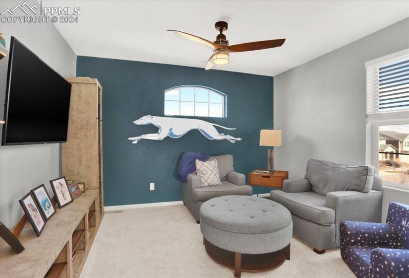 Loft area with ceiling fan, a wealth of natural light, and light carpet