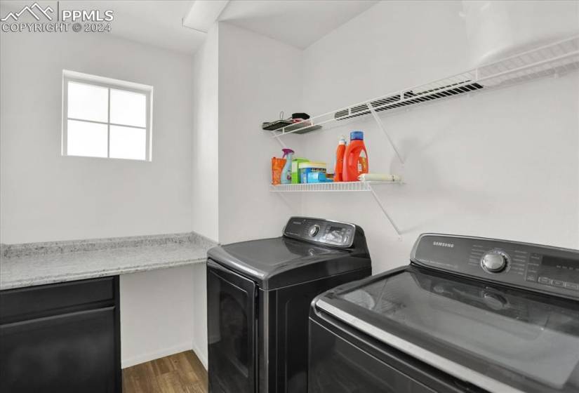 Laundry area featuring dark hardwood / wood-style flooring, washing machine and clothes dryer, and cabinets