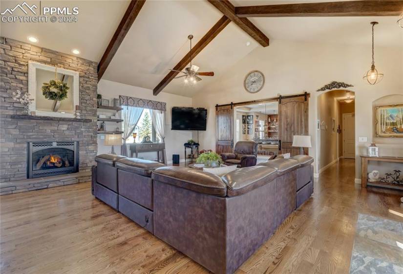 Great Room w/Soaring, Beamed Ceilings, Gleaming Hardwood Floors + Gas Fireplace with Floor-to-Ceiling Stone Surround