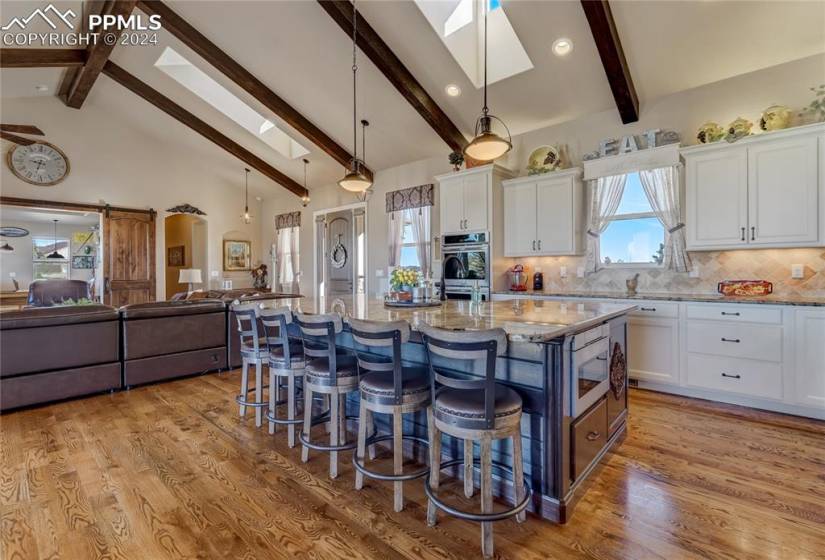 Granite Countertops | Travertine Backsplash | Custom Cabinets w/Crown Molding + Under Cabinet Lighting | 5 Burner Gas Cooktop | Custom Vent Hood | Double Wall Ovens | Drawer Microwave | Large Center Island w/Tongue + Groove Wood Accent Surround, Ample Room for Seating + Copper Sink | Walk-in Pantry