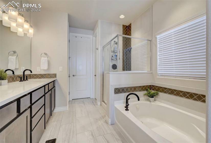 Primary Bathroom with shower with separate bathtub, tile floors, and vanity