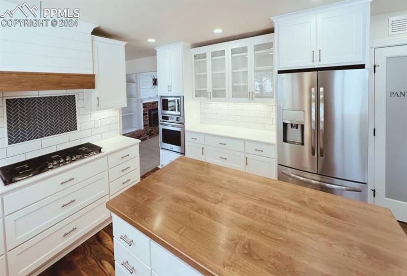 Kitchen with wooden counters, white cabinetry, stainless steel appliances, and tasteful backsplash