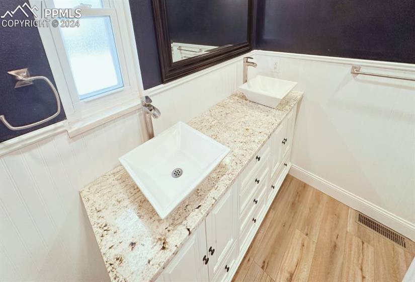 Bathroom featuring hardwood / wood-style flooring and vanity with extensive cabinet space