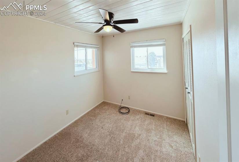 Carpeted spare room featuring wooden ceiling, ceiling fan, and a healthy amount of sunlight
