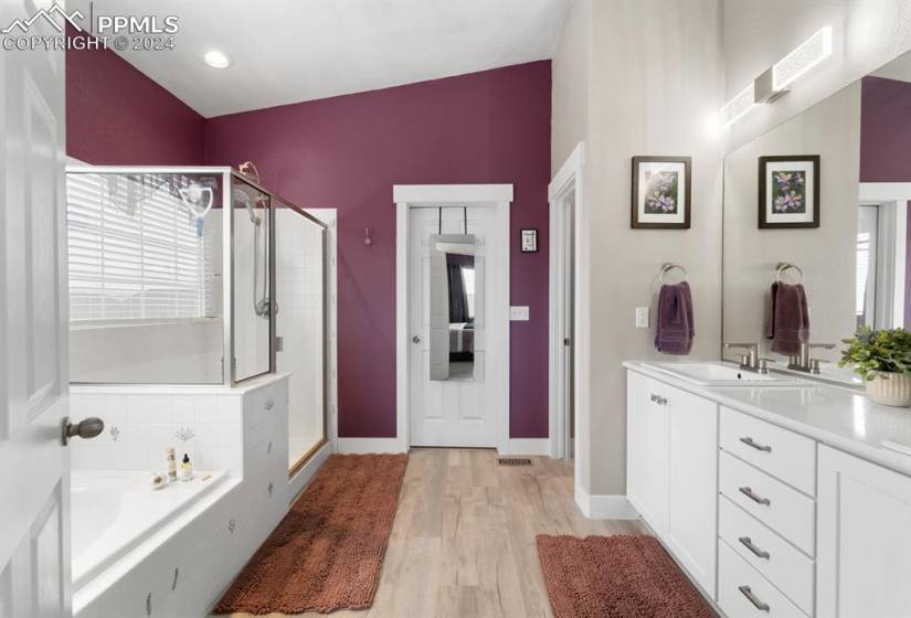 Bathroom featuring hardwood / wood-style floors, vanity, separate shower and tub, and vaulted ceiling
