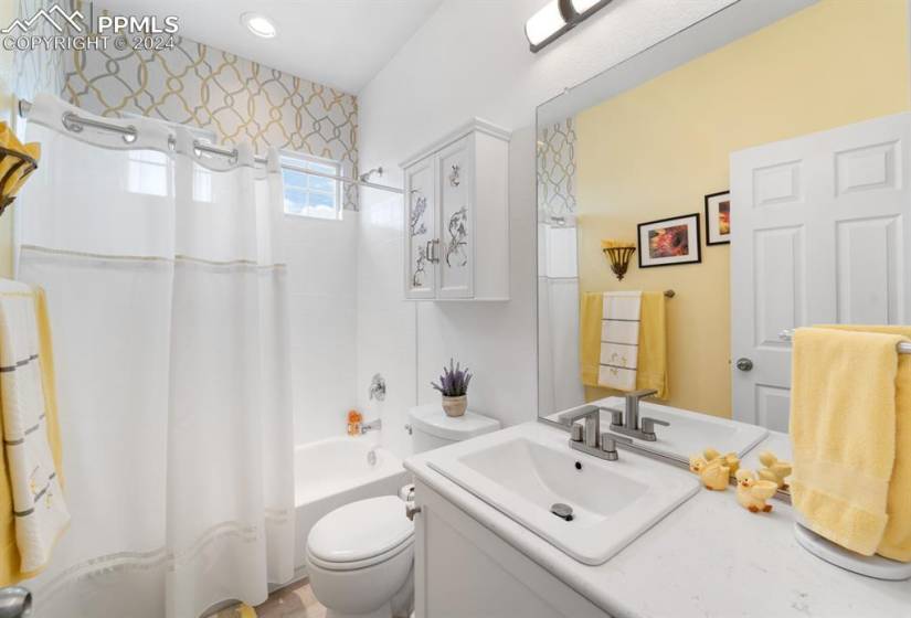 Full bathroom with shower / tub combo, toilet, and vanity with extensive cabinet space