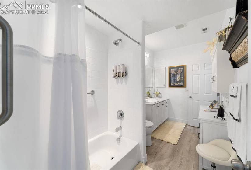 Full bathroom with shower / bathtub combination with curtain, toilet, hardwood / wood-style flooring, and vanity