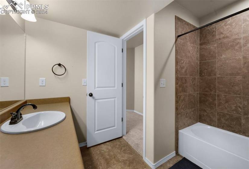 Bathroom featuring tiled shower / bath, tile floors, and vanity