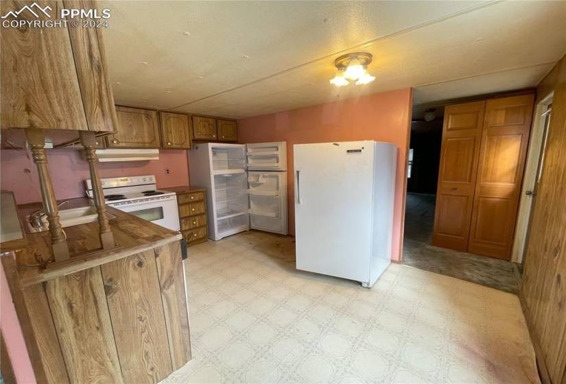 Kitchen featuring vinyl flooring, breakfast bar, and white appliances