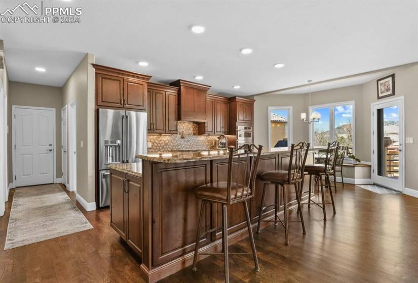 Kitchen with a breakfast bar, dark wood-type flooring, appliances with stainless steel finishes, and tasteful backsplash