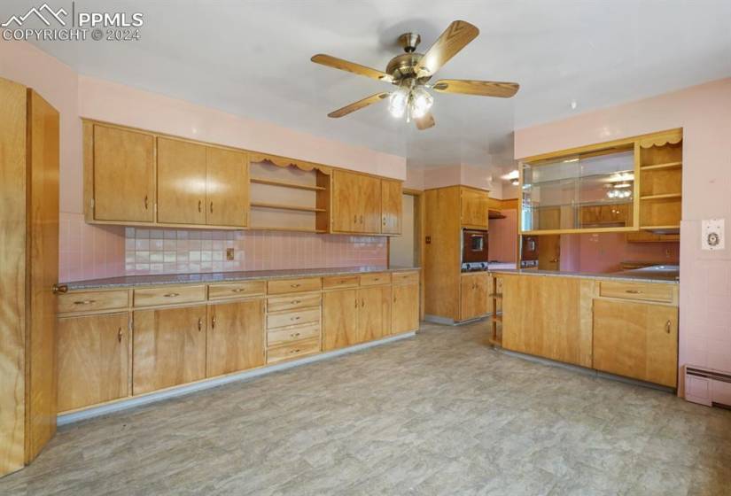 Kitchen featuring tasteful backsplash, ceiling fan, light tile floors, a baseboard heating unit, and kitchen peninsula