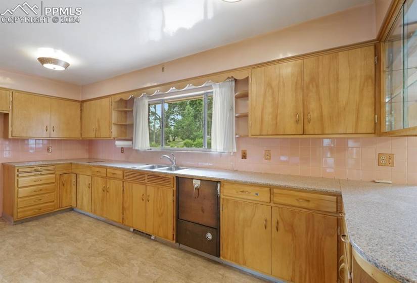 Kitchen featuring sink, backsplash, light tile flooring, and light stone counters