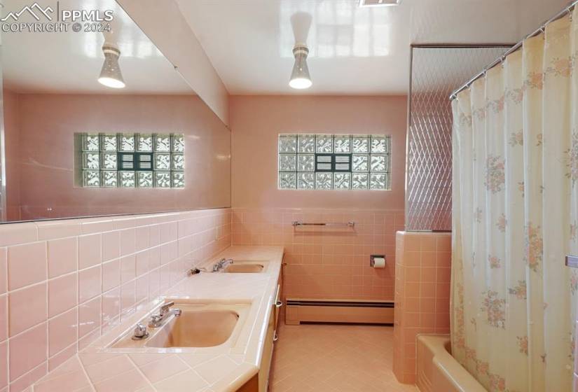 Bathroom with tile walls, tasteful backsplash, a baseboard heating unit, and tile floors