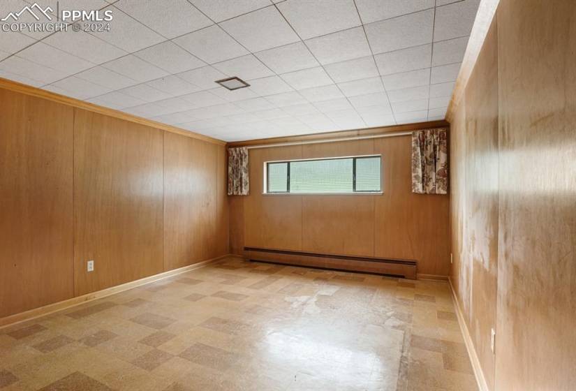 Tiled empty room featuring a baseboard radiator and wooden walls