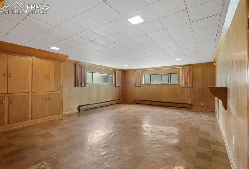 Spare room featuring a baseboard radiator, wood walls, and light tile flooring