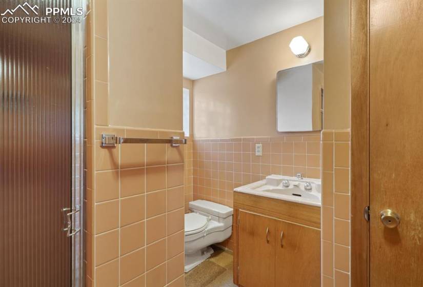 Bathroom featuring toilet, tile walls, large vanity, and tasteful backsplash
