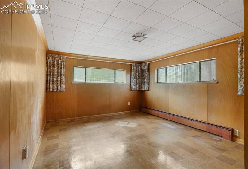 Unfurnished room with light tile flooring, baseboard heating, and wooden walls