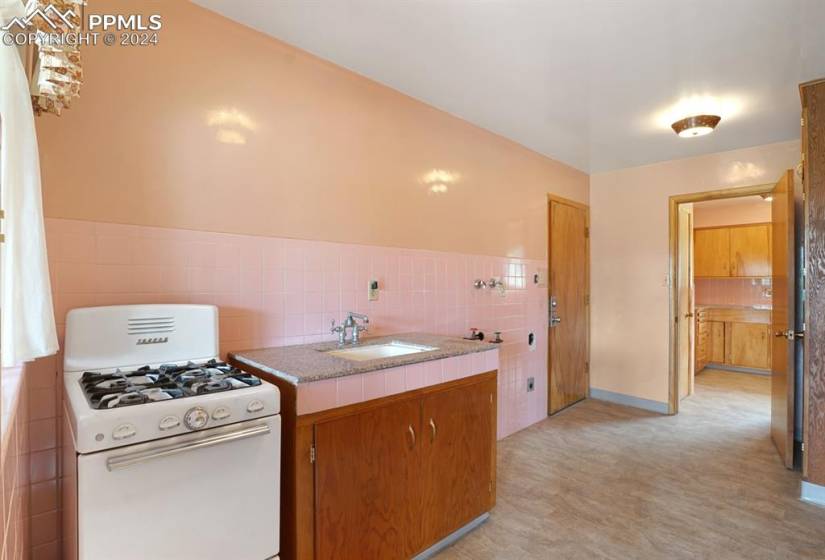 Kitchen featuring light tile flooring, gas range gas stove, sink, tasteful backsplash, and tile countertops