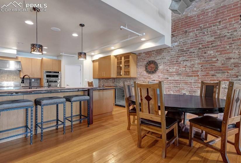 Dining area with wine cooler, brick wall, and original wood flooring