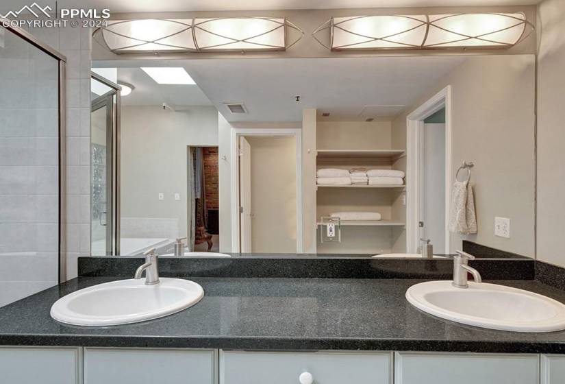 Bathroom with a soaker jetted tub, double vanity, and standalone shower. Skylight beings lots of natural light.