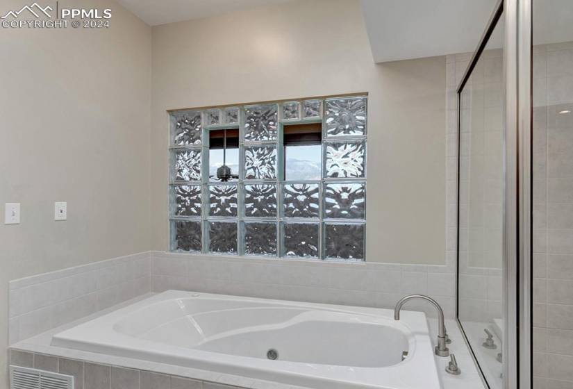 Bathroom with a soaker jetted tub, double vanity, and standalone shower. Skylight beings lots of natural light.