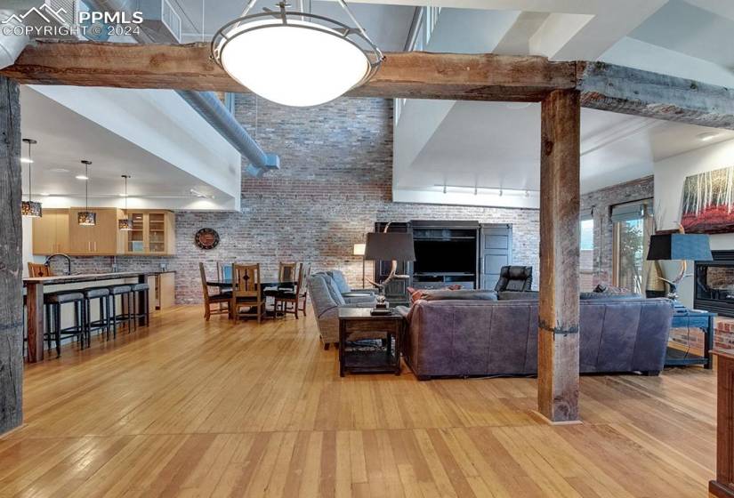Living room featuring beamed ceiling, original hardwood, and exposed brick wall.