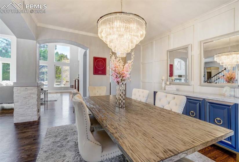 Dining room featuring dark wood-type flooring, ornamental molding, and a chandelier