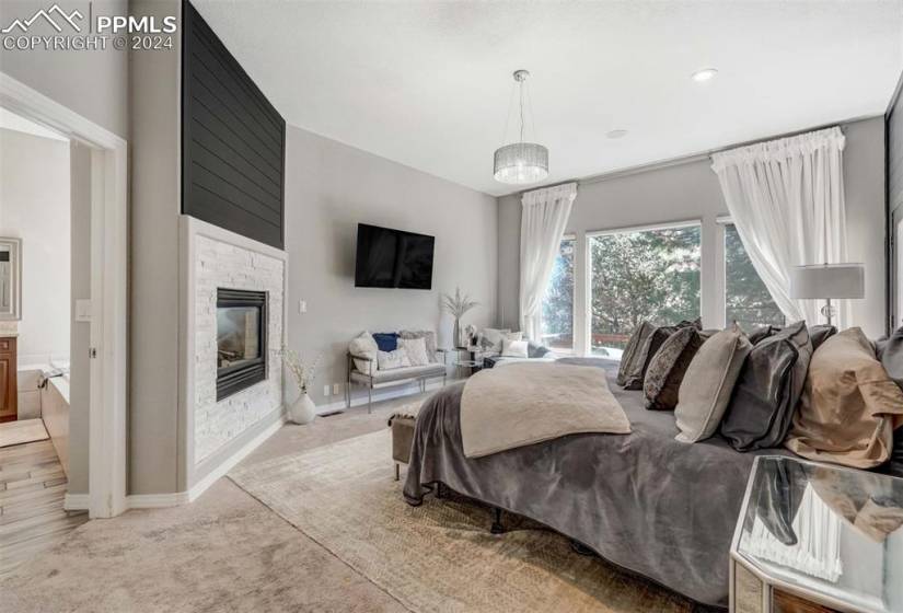 Bedroom featuring a notable chandelier, a fireplace, connected bathroom, and light hardwood / wood-style floors