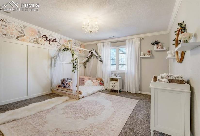 Unfurnished bedroom featuring an inviting chandelier, ornamental molding, carpet, and a textured ceiling