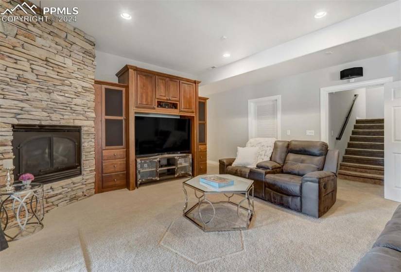 Carpeted living room featuring a stone fireplace