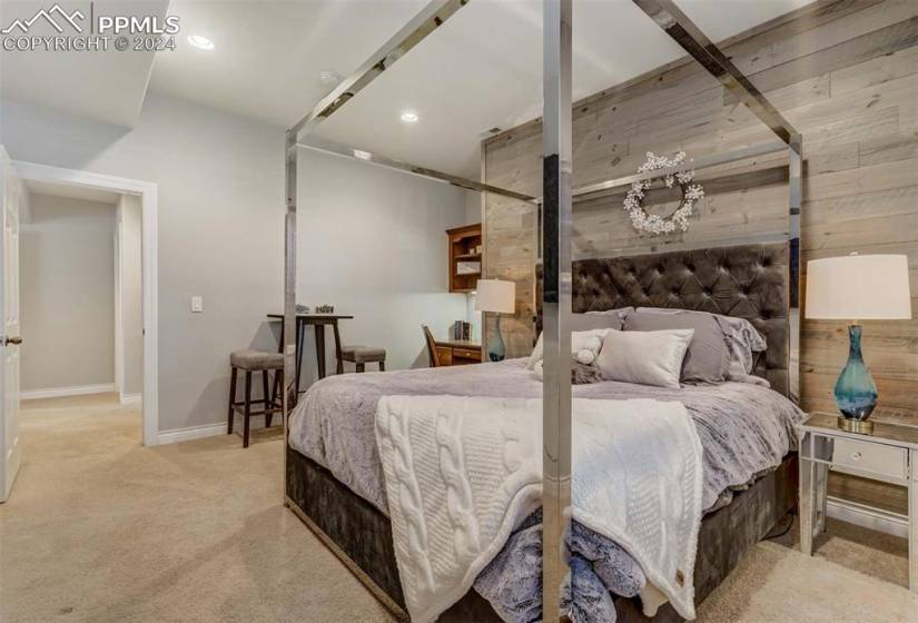 Bedroom featuring light colored carpet and wood walls