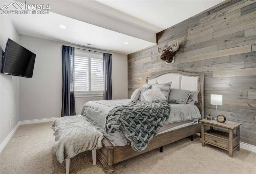 Bedroom featuring wood walls and light carpet