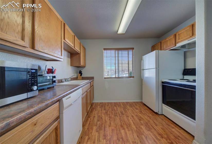 Kitchen with sink, white appliances, and light wood-type flooring