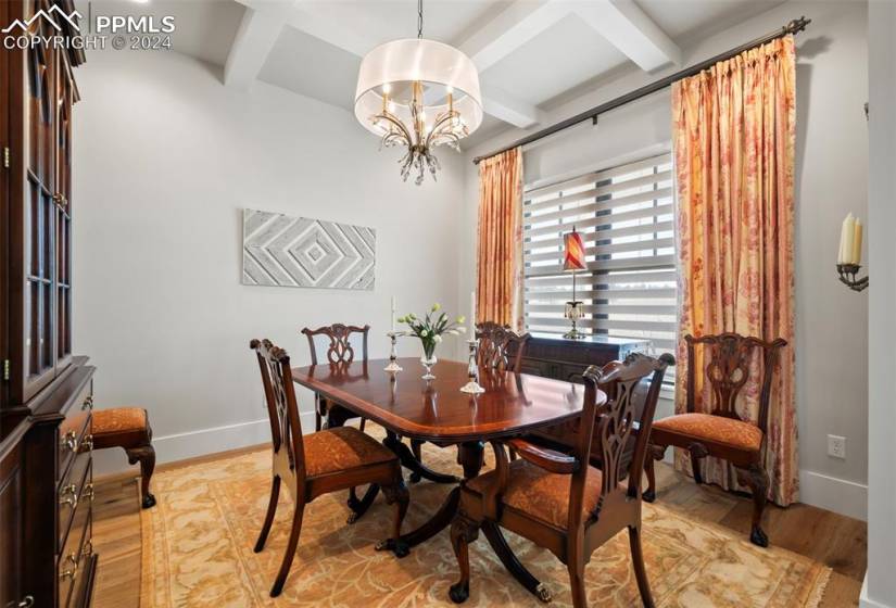 Dining room featuring an inviting chandelier, light hardwood / wood-style flooring, beam ceiling, and coffered ceiling