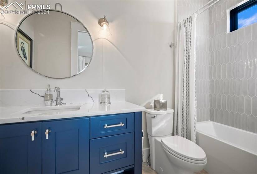 Full bathroom with large vanity, toilet, and shower / bath combo with shower curtain