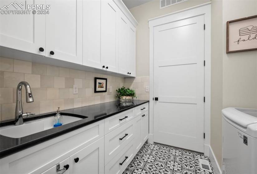 white cabinets, sink, light tile flooring, and washer / clothes dryer
