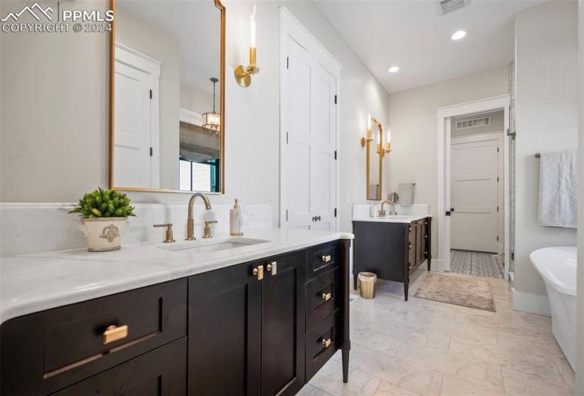 Bathroom featuring marble countertops, tile floors, custom vanity, and a tub