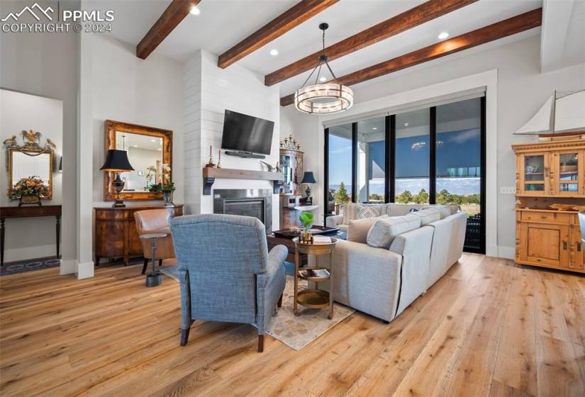 Living room with beamed ceiling, light hardwood / wood-style floors, and a fireplace