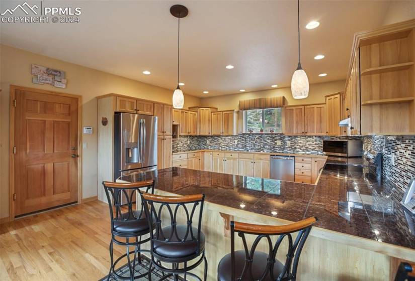 Kitchen featuring hanging light fixtures, appliances with stainless steel finishes, and a breakfast bar